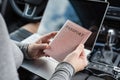 Woman in the car with laptop and passport in a pink cover. Travel concept. Royalty Free Stock Photo