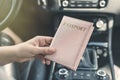 Woman in the car with laptop and passport in a pink cover. Travel concept. Royalty Free Stock Photo