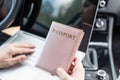 Woman in the car with laptop and passport in a pink cover. Travel concept. Royalty Free Stock Photo