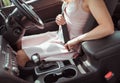 A woman in a car sits behind the wheel, in the summer in the city. Fastens seat belt, right-hand drive, left-hand drive Royalty Free Stock Photo