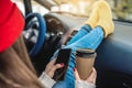 Woman in a car in warm socks is holding a mobile phone gadget. Cozy autumn weekend trip. Freedom of travel Royalty Free Stock Photo