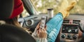 Woman in a car in warm socks is holding a mobile phone gadget. Cozy autumn weekend trip. Freedom of travel Royalty Free Stock Photo