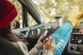 Woman in a car in warm socks is holding a mobile phone gadget. Cozy autumn weekend trip. Freedom of travel Royalty Free Stock Photo