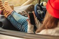 Woman in a car in warm socks is holding a mobile phone gadget at sunset. Cozy autumn weekend trip. Freedom of travel Royalty Free Stock Photo