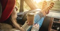 Woman in a car in warm socks yellow is holding a Cup of coffee in hands at sunset. Cozy autumn weekend trip Royalty Free Stock Photo