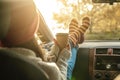 Woman in a car in warm socks yellow is holding a Cup of coffee in hands at sunset. Cozy autumn weekend trip Royalty Free Stock Photo