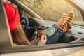 Woman in a car in warm socks yellow is holding a Cup of coffee in hands at sunset. Cozy autumn weekend trip Royalty Free Stock Photo