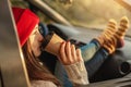 Woman in a car in warm socks yellow is holding a Cup of coffee in hands at sunset. Cozy autumn weekend trip Royalty Free Stock Photo