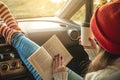 Woman in a car in warm woolen socks yellow is reading a book at sunset. Cozy autumn weekend trip. Freedom of travel Royalty Free Stock Photo