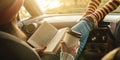 Woman in a car in warm woolen socks yellow is reading a book at sunset. Cozy autumn weekend trip. Freedom of travel Royalty Free Stock Photo