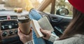 Woman in a car in warm woolen socks yellow is reading a book at sunset. Cozy autumn weekend trip. Freedom of travel Royalty Free Stock Photo