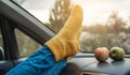 Woman in a car in warm woolen yellow socks on the car dashboard. Cozy autumn weekend trip. Concept of freedom of travel Royalty Free Stock Photo