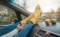 Woman in a car in warm woolen yellow socks on the car dashboard. Cozy autumn weekend trip. Concept of freedom of travel Royalty Free Stock Photo