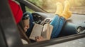 Woman in a car in warm yellow socks is reading a book while sitting in the passenger seat. Cozy autumn weekend trip Royalty Free Stock Photo