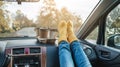 Woman in a car in warm yellow socks is holding a Cup of coffee in hands. Cozy autumn weekend trip. Freedom of travel Royalty Free Stock Photo