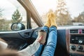 Woman in a car in warm yellow socks is holding a Cup of coffee in hands. Cozy autumn weekend trip. Freedom of travel Royalty Free Stock Photo