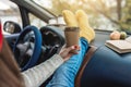 Woman in a car in warm yellow socks is holding a Cup of coffee in hands. Cozy autumn weekend trip. Freedom of travel Royalty Free Stock Photo