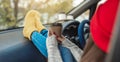 Woman in a car in warm yellow socks is holding a Cup of coffee in hands. Cozy autumn weekend trip. Freedom of travel Royalty Free Stock Photo