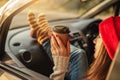 Woman in a car in warm yellow socks is holding a Cup of coffee in hands. Cozy autumn weekend trip. Freedom of travel Royalty Free Stock Photo