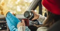 Woman in a car in warm yellow socks is pouring coffee from a thermos into a Cup. Cozy autumn weekend trip