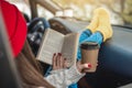 Woman in a car in warm yellow socks is reading a book while sitting in the passenger seat. Cozy autumn weekend trip Royalty Free Stock Photo