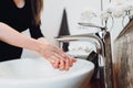 Woman carefully washing hands with soap and sanitiser in home bathroom