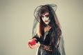 Woman in a carnival costume of a witch or a dead bride holding an apple in her hands, gothic woman in witch costume on gray Royalty Free Stock Photo