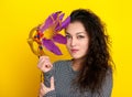 Woman in carnival mask with feather, beautiful girl portrait on yellow color background, long curly hair Royalty Free Stock Photo