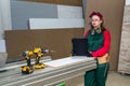 Woman carpenter with drill machine at workplace