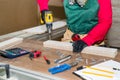 Woman carpenter making hole in wooden plank.