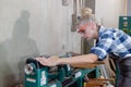 Woman carpenter wear uniform and goggles using wood turning machine. craftsman profession in wood factory. female worker lathe