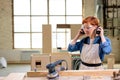 woman carpenter wearing headset before woodworking, cutting wood using power saw Royalty Free Stock Photo