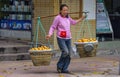 Woman carries 2 baskets of fruits on shoulder pole, Chongqing, China