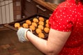 A woman carries cooked buns on a baking sheet. The woman in the kitchen made bread rolls