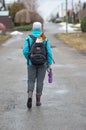 Woman carrying Basenji dog inside backpack while walking on wet road