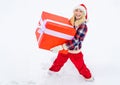 Woman carrying a big present isolated on snow winter background - full length. Funny woman holding a big Christmas