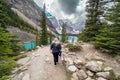 Woman carrying camera gear walks the Rockpile Trail at Moraine Lake in Banff National Park