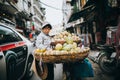 woman carrying fruits on bicycle on busy street in Hanoi, Vietnam