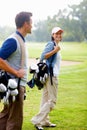 Woman carrying golf bag. Focus on smiling woman carrying golf bag and looking at man. Royalty Free Stock Photo