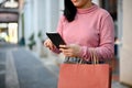 Woman carrying her shopping bags and using her smartphone while shopping at the city square Royalty Free Stock Photo