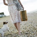 Woman carrying picnic basket with dog following from behind. Conceptual image Royalty Free Stock Photo