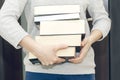 Woman carrying a pile of thick books for reading