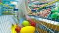 Woman with cart or trolley buying fresh vegetables and fruits at supermarket Royalty Free Stock Photo