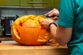 Woman carving a minion into a halloween pumpkin in the kitchen