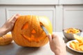 Woman carving pumpkin head Jack lantern for Halloween at light table indoors Royalty Free Stock Photo