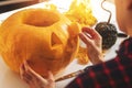 Woman carving pumpkin into jack-o-lantern for halloween holiday decoration at home kitchen