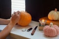 Woman carving pumpkin on the table in the home. Family preparing for holiday, process of making Jack O Lantern for Halloween