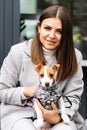 Woman in casual jacket hugging her favorite fluffy trained purebred Jack Russell Terrier dog dressed in suit for dogs outdoors, in Royalty Free Stock Photo