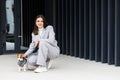 Woman in casual jacket sitting near her favorite fluffy trained purebred Jack Russell Terrier dog dressed in suit for dogs near Royalty Free Stock Photo
