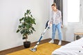 Woman in casual wear vacuum cleaning yellow carpet, tidying white modern living room. Home, housekeeping concept Royalty Free Stock Photo